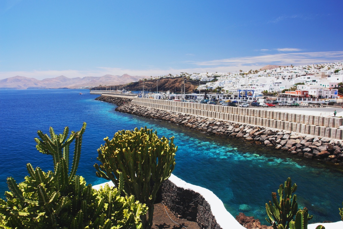 Puerto del Carmen en Lanzarote, con barcos en el agua y restaurantes junto al mar.